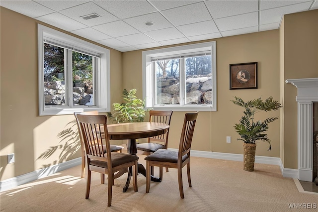 dining space featuring plenty of natural light, a paneled ceiling, baseboards, and light carpet