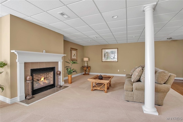 carpeted living room featuring visible vents, baseboards, a tiled fireplace, decorative columns, and a paneled ceiling