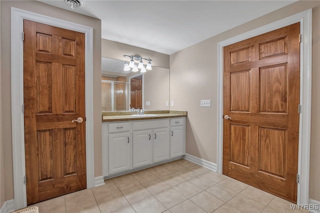 bathroom with tile patterned floors, visible vents, a shower with door, baseboards, and vanity