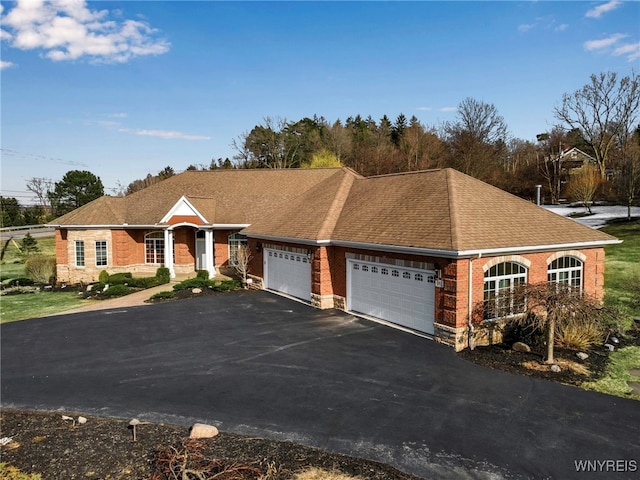 single story home with brick siding, an attached garage, a shingled roof, and driveway