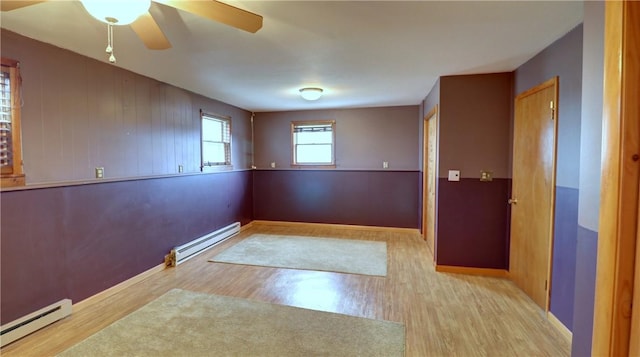 unfurnished room featuring a ceiling fan, wood finished floors, and baseboard heating