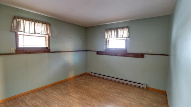 unfurnished room with a wealth of natural light, wood finished floors, baseboards, and baseboard heating