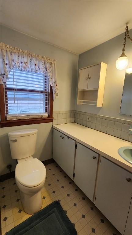 bathroom with vanity, baseboards, decorative backsplash, tile patterned floors, and toilet