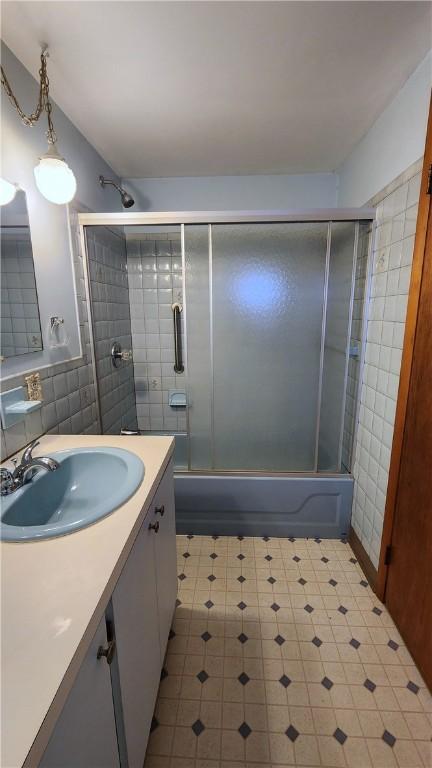 full bathroom with combined bath / shower with glass door, vanity, and tile patterned floors