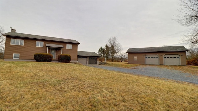 bi-level home featuring a chimney, a front yard, a garage, and an outdoor structure