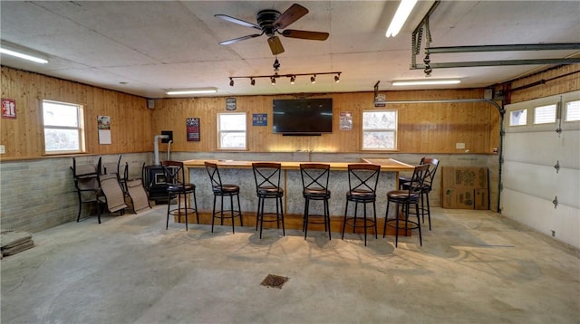 bar with concrete flooring, wood walls, and a ceiling fan