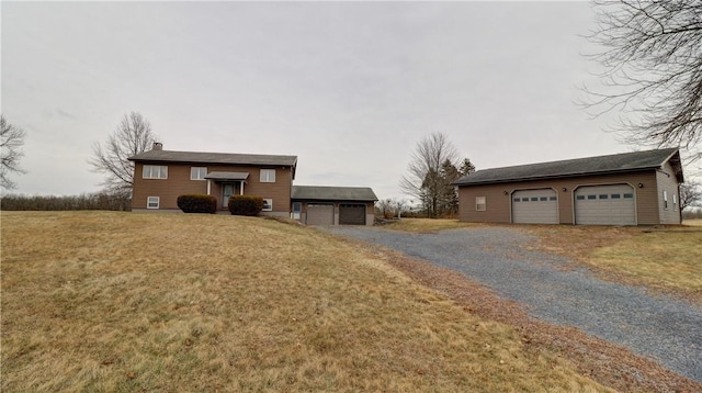 split foyer home featuring a detached garage, an outbuilding, a front lawn, and a chimney