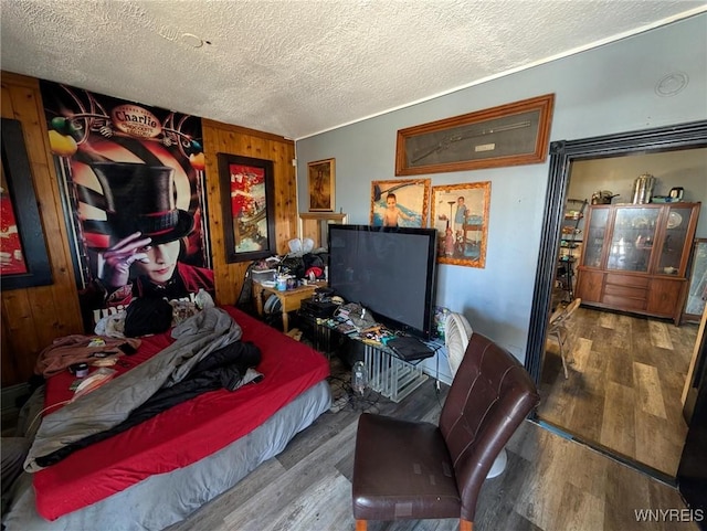 bedroom featuring a textured ceiling, wood finished floors, and wood walls