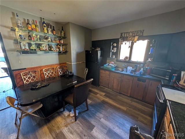 interior space featuring range, dark countertops, dark wood-style flooring, and freestanding refrigerator