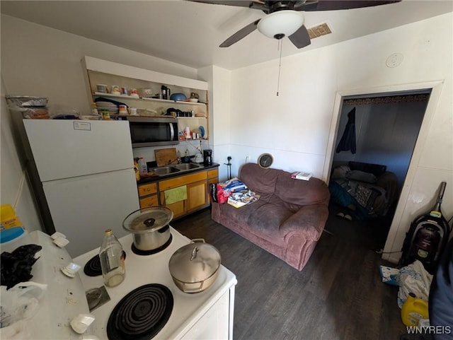 living room with visible vents, dark wood-type flooring, and a ceiling fan