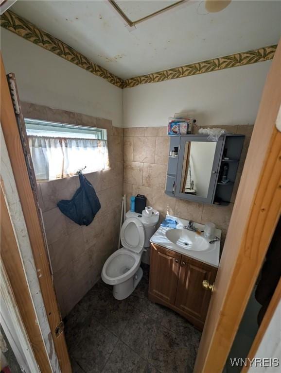 bathroom featuring toilet, tile walls, and vanity