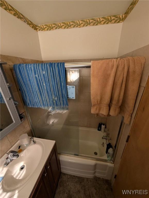 full bath with shower / bath combination with glass door, vanity, and tile patterned flooring