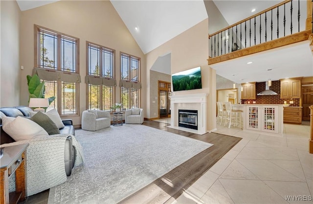 living area with light tile patterned floors, a fireplace with flush hearth, recessed lighting, and high vaulted ceiling