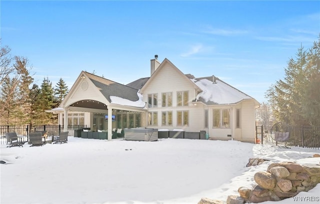 snow covered rear of property with a chimney and fence