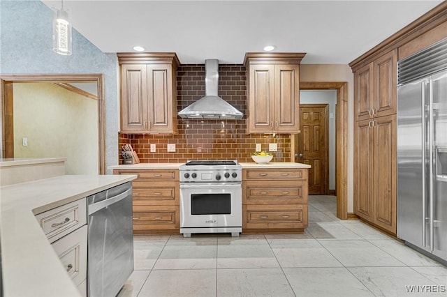 kitchen featuring recessed lighting, light countertops, wall chimney exhaust hood, premium appliances, and backsplash