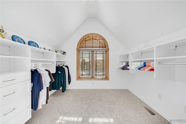 spacious closet with carpet flooring, visible vents, and vaulted ceiling