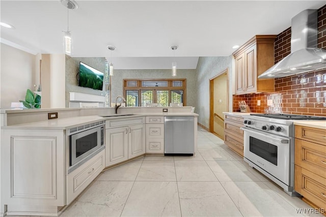 kitchen with a sink, decorative backsplash, light countertops, stainless steel appliances, and wall chimney range hood