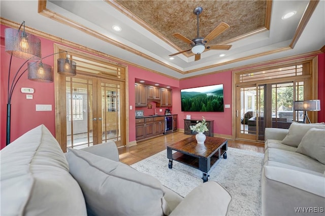 living area with beverage cooler, a tray ceiling, french doors, crown molding, and baseboards