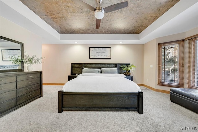 carpeted bedroom featuring access to exterior, a tray ceiling, and baseboards