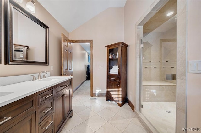 bathroom with vaulted ceiling, double vanity, a stall shower, tile patterned floors, and a sink