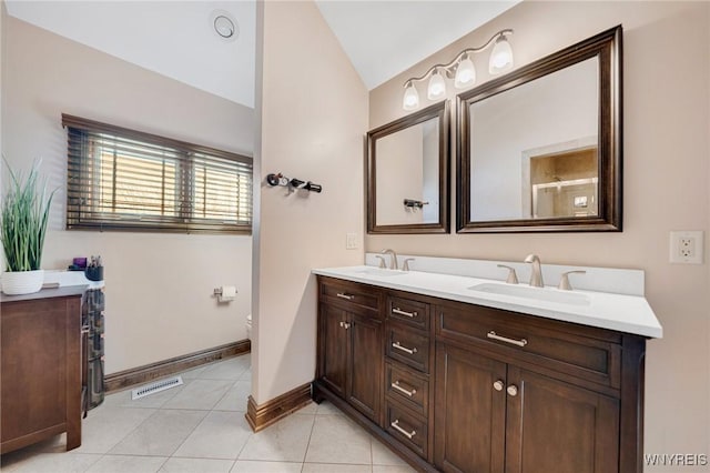 bathroom featuring a sink, lofted ceiling, double vanity, and tile patterned flooring