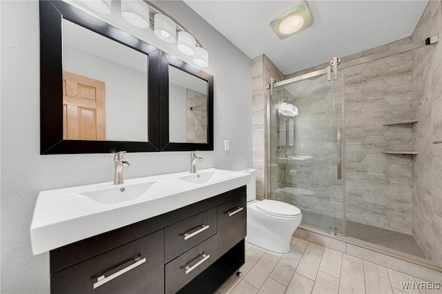 full bath featuring double vanity, a stall shower, toilet, and a sink