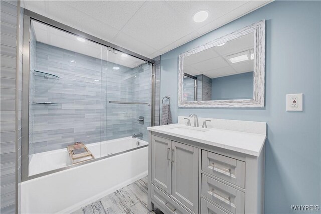 bathroom featuring wood finished floors, vanity, a paneled ceiling, and bath / shower combo with glass door