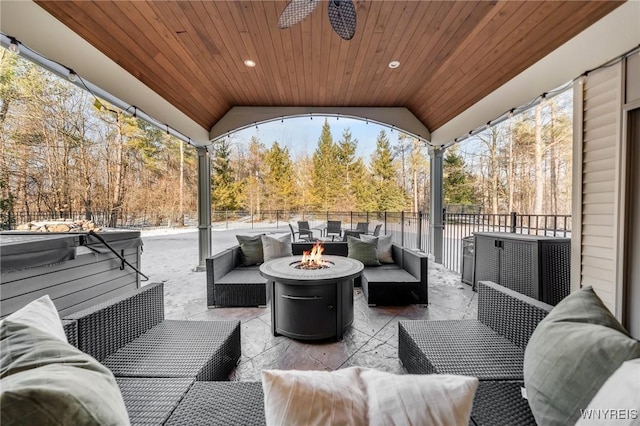 view of patio / terrace with an outdoor living space with a fire pit, a ceiling fan, and a hot tub