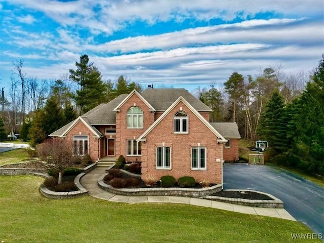 traditional-style house featuring brick siding, aphalt driveway, and a front lawn