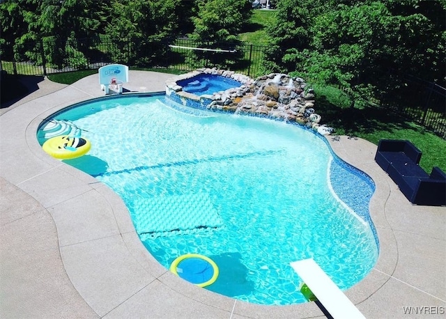 view of swimming pool with a patio area, a fenced backyard, a diving board, and a pool with connected hot tub