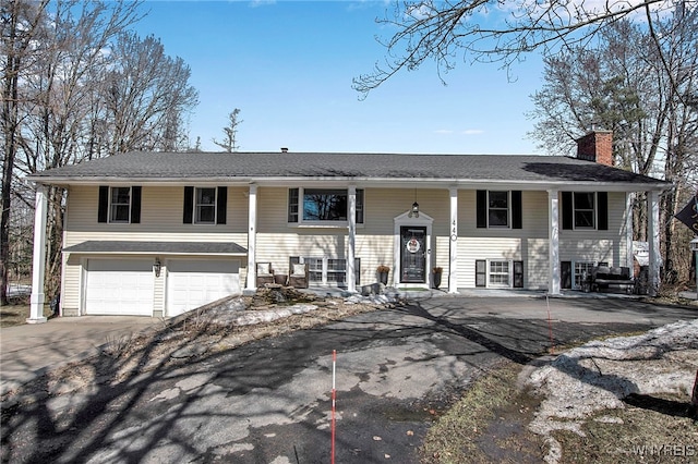 bi-level home with a chimney, concrete driveway, and a garage