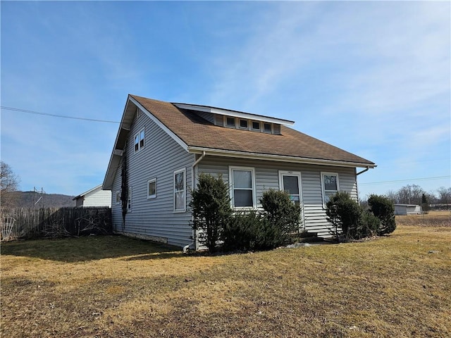 exterior space featuring a lawn and a shingled roof