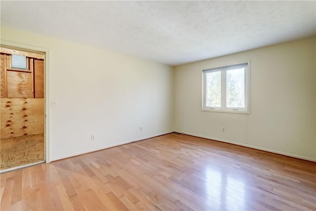 unfurnished room with wood finished floors, baseboards, and a textured ceiling