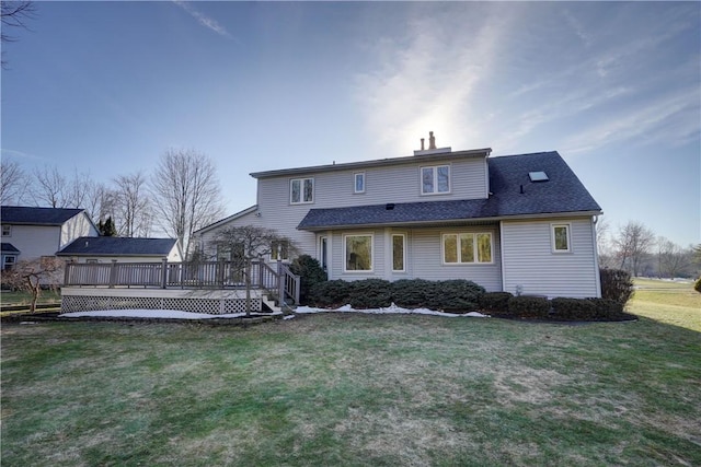 rear view of house featuring a yard, roof with shingles, and a wooden deck