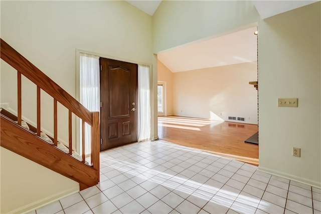 entryway with high vaulted ceiling, light tile patterned flooring, and stairs