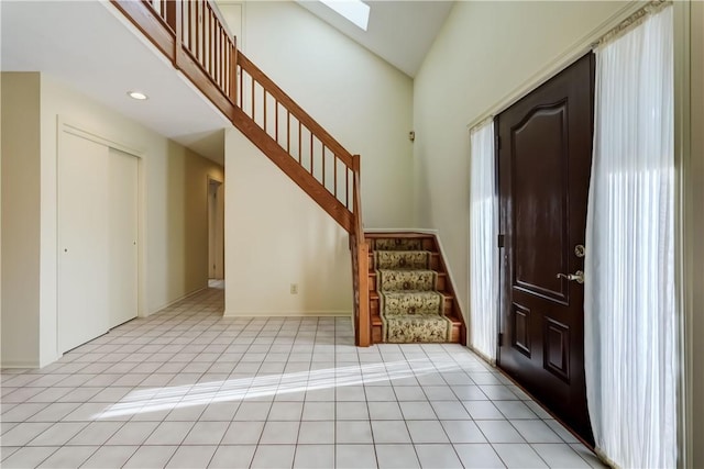 entrance foyer with recessed lighting, stairway, a skylight, light tile patterned floors, and a towering ceiling