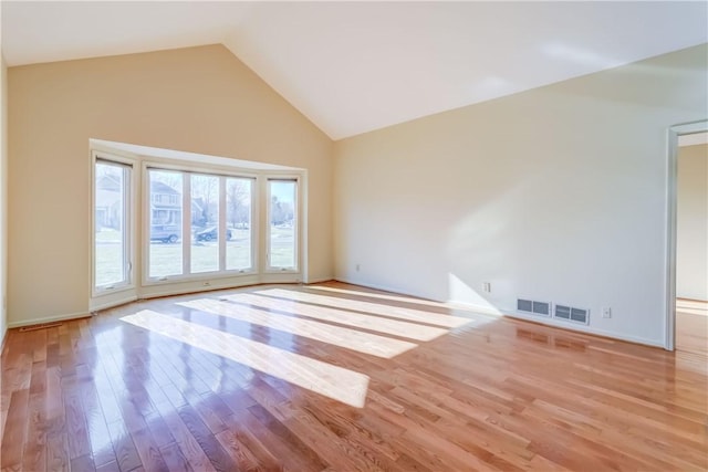 empty room featuring high vaulted ceiling and wood finished floors