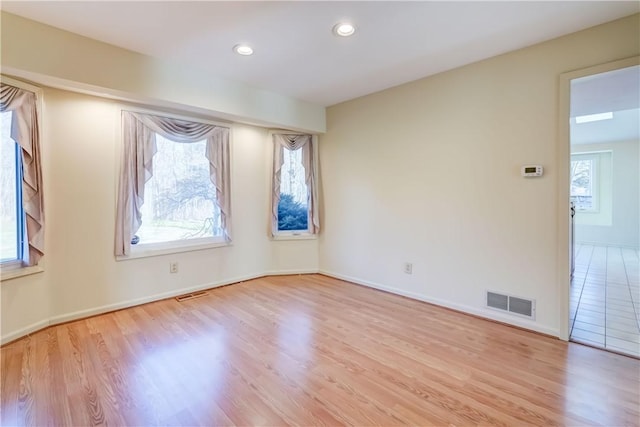 empty room with visible vents, plenty of natural light, and wood finished floors