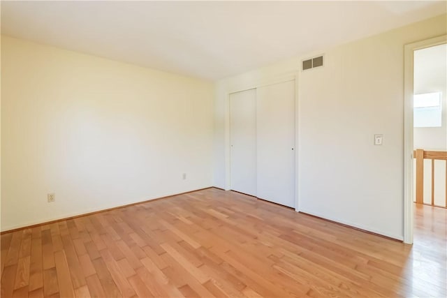 unfurnished bedroom featuring visible vents, a closet, and light wood-style flooring