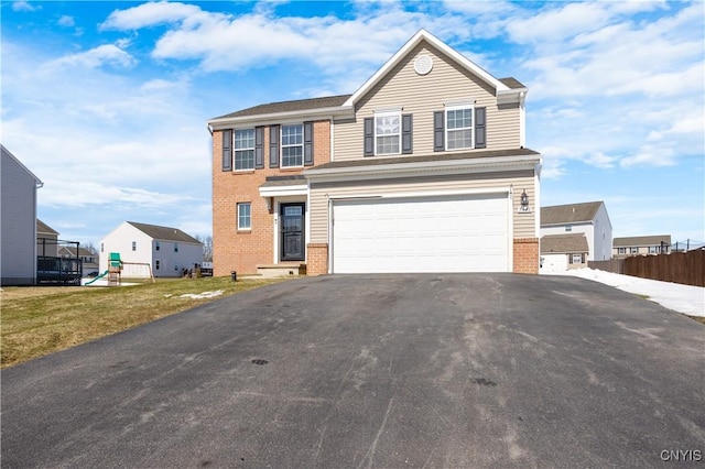 traditional home featuring a garage, brick siding, driveway, and fence