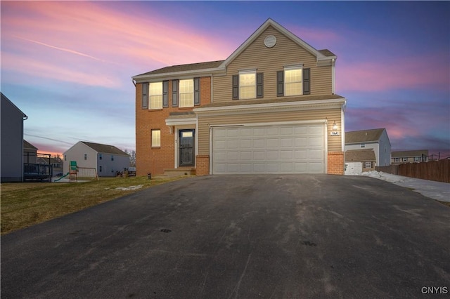 traditional home with brick siding, an attached garage, driveway, and fence