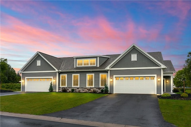 craftsman-style home with aphalt driveway, an attached garage, a front yard, and roof with shingles