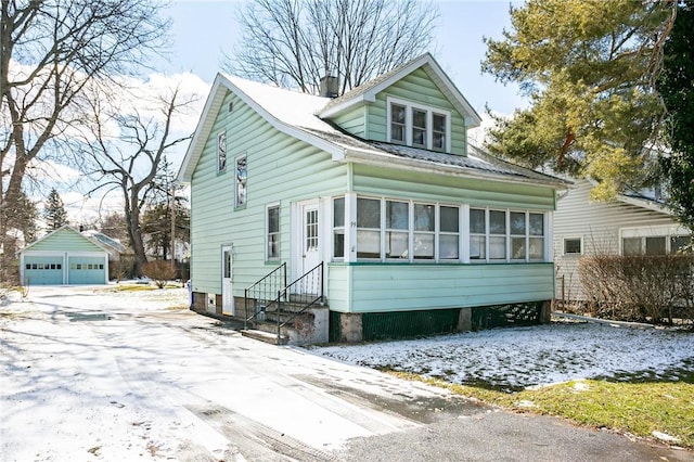 view of front facade featuring a garage, a sunroom, an outdoor structure, and entry steps