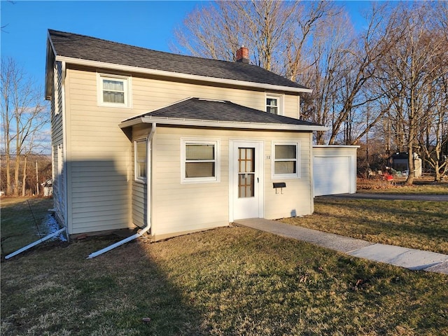 view of front of property featuring a shingled roof, a front lawn, a garage, and a chimney