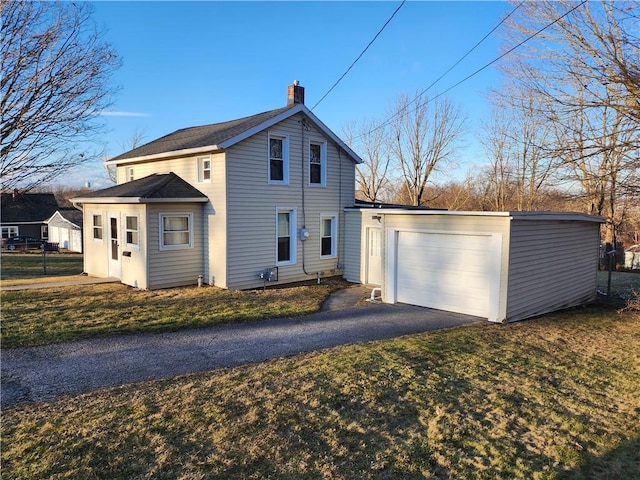 exterior space with a lawn, driveway, a chimney, and a garage