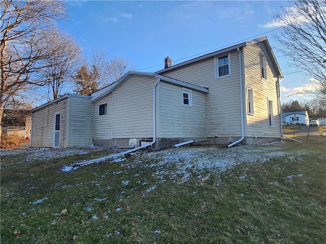 back of property with a lawn and a chimney