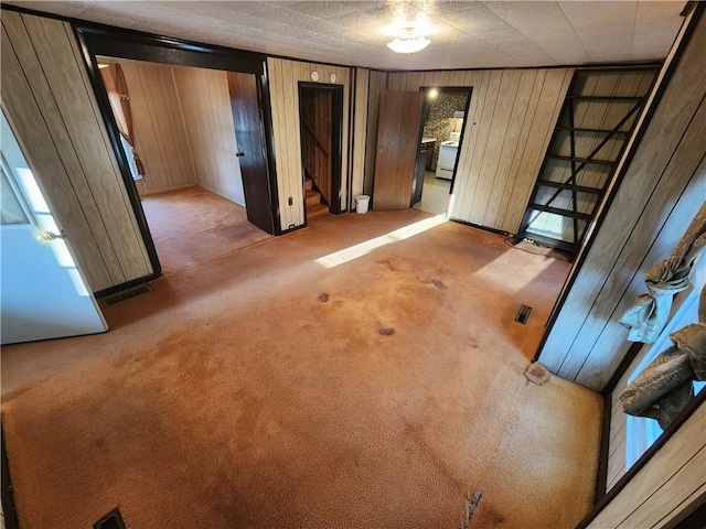 unfurnished bedroom featuring light carpet, wooden walls, and visible vents