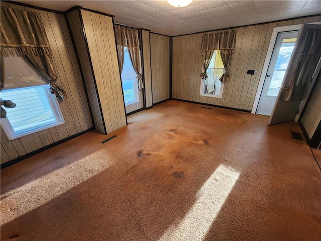 spare room with visible vents, light carpet, and wooden walls