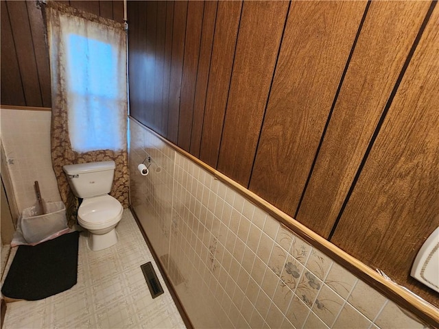 bathroom with tile walls, toilet, visible vents, and tile patterned floors