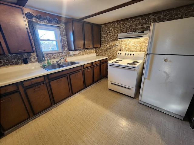 kitchen featuring a sink, range hood, white appliances, dark brown cabinetry, and light floors